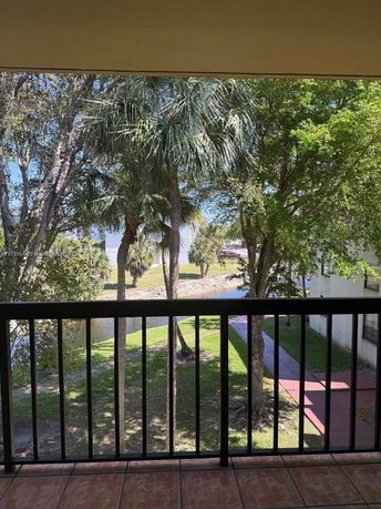 View from a balcony showing trees and a grassy area.