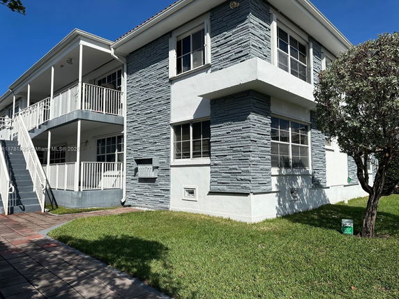 Front view of a two-story building with a stone facade and exterior staircase.
