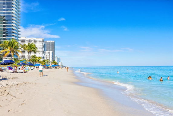 Beachfront view with tall buildings and people enjoying the shore.