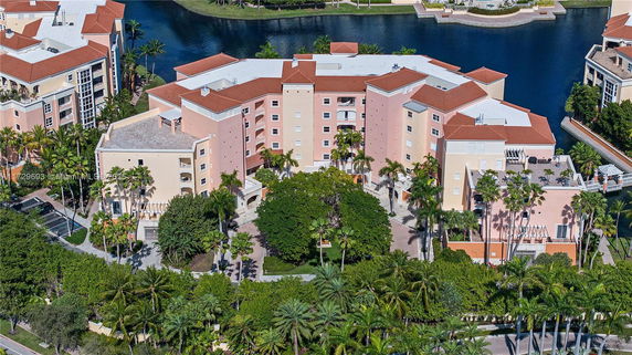 Aerial view of a multi-story building complex with red-tiled roofs near a body of water.