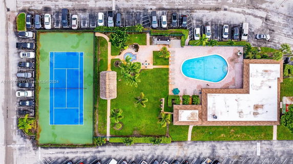 Aerial view of a complex with a tennis court, swimming pool, and parking area.
