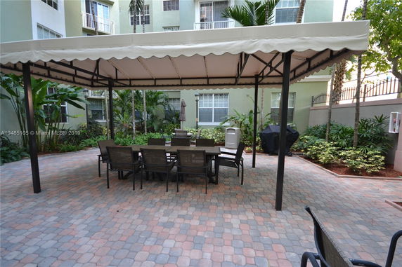 Outdoor patio area with covered seating surrounded by a multi-story residential building.