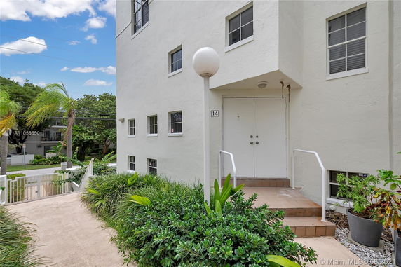 Entrance of a multi-story building with large white doors and multiple windows.