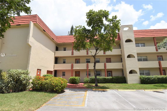 Front view of a multi-story apartment building with balconies and a red-tiled roof.