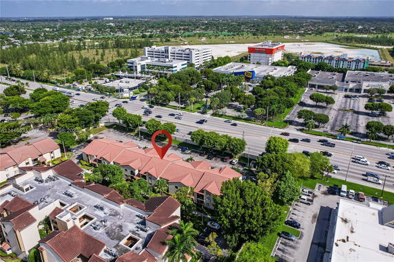 Aerial view of a commercial and residential area with roads and parking.