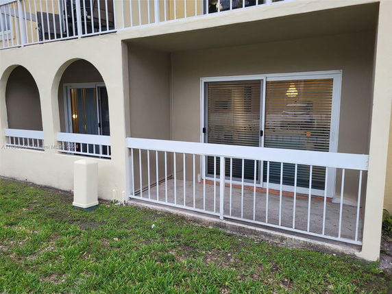Front view of a building with a patio area and sliding glass doors.