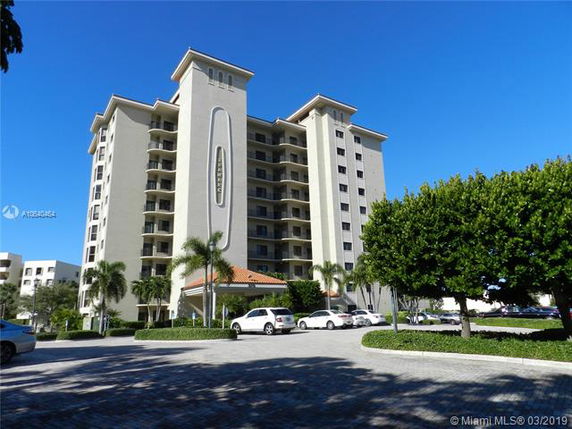 Front view of a multi-story apartment building with a covered entrance.