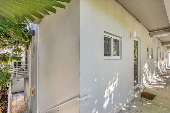 Exterior view of a building corridor with doors and windows.