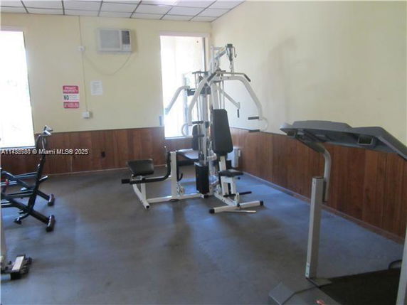 Room with gym equipment including a treadmill and weight machine.