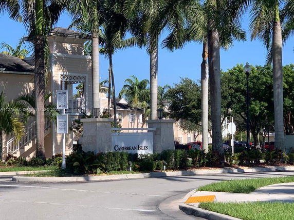 Front view of a building with tall palm trees and an entrance sign reading 'Caribbean Isles'.