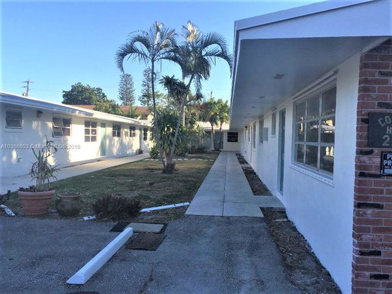 Front view of a single-story residential building with a pathway and potted plants.