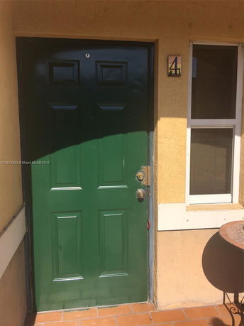 Front view of a building entrance with a green door and a window.