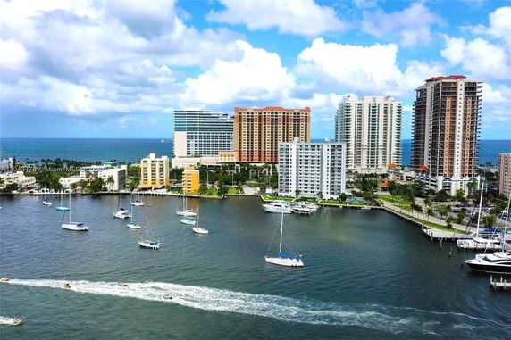 Panoramic view of waterfront buildings and sailboats with a clear blue sky.