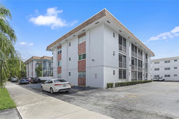 Front view of a three-story apartment building with a white and brick exterior.