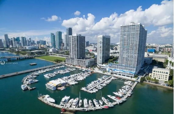 Aerial view of a marina with several high-rise buildings and a city skyline in the background.