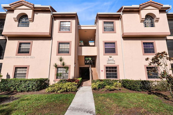 Front view of a multi-story apartment building with beige walls and red-brown accents.