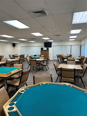 Interior view of a room with multiple tables and chairs arranged for recreation or meetings.