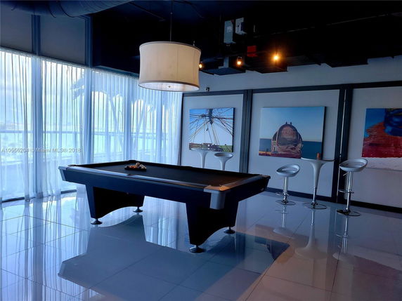 Interior view of a recreational room with a pool table and high stools.