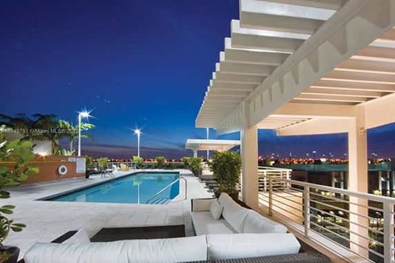 Rooftop area featuring a pool, seating area, and modern pergola at dusk.