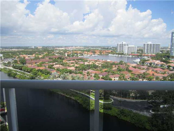 Panoramic view of a neighborhood from a high vantage point with water, trees, and multiple buildings visible.