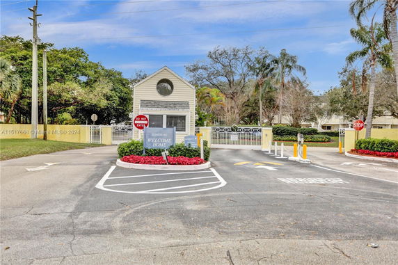 Front view of a security booth at the entrance of a residential area with signage and gate.