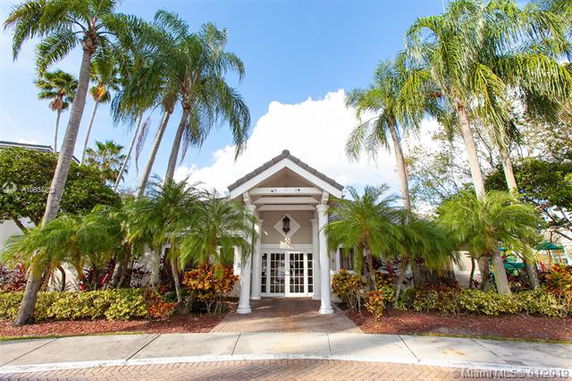 Front view of a house with multiple columns and surrounding palm trees.