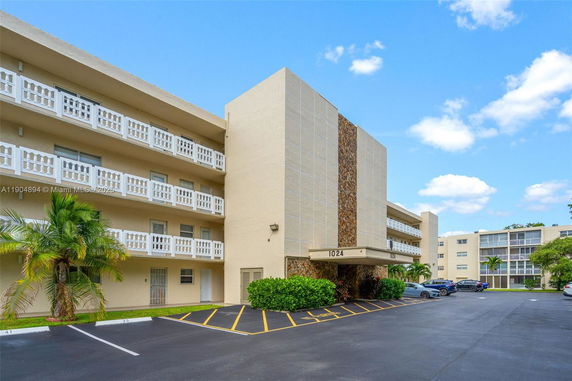 Front view of a multi-story building with white railings and a covered entrance.