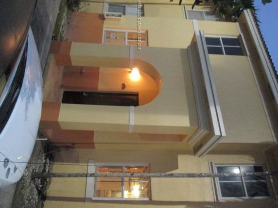 Front view of a two-story house with arched doorway and lit entrance.