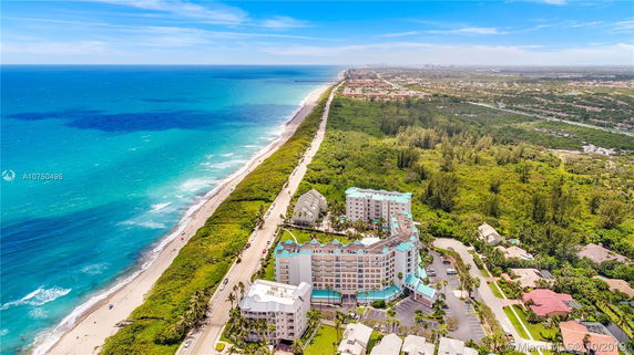 Aerial view of a coastal area with buildings near the beach and lush greenery.
