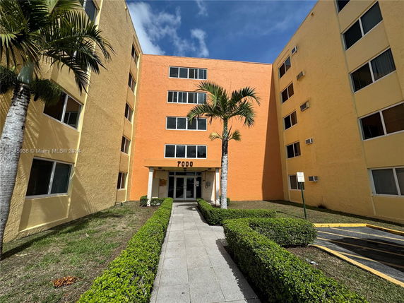Front view of a multi-story apartment building with orange and yellow facade.