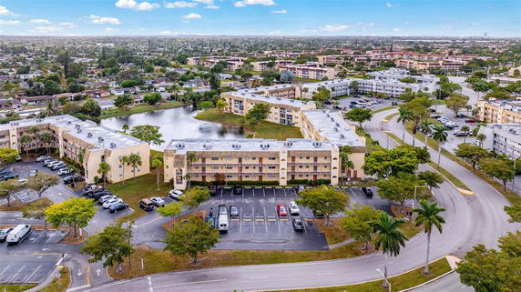 Aerial view of a residential area with multiple apartment buildings near a pond, surrounded by roads and greenery.
