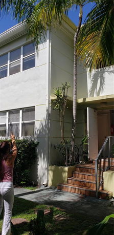 Front view of a two-story building with open doorway and stairs.