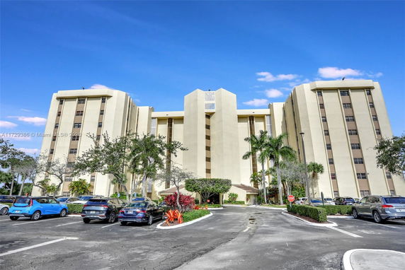 Front view of a multi-story beige building with parking area.