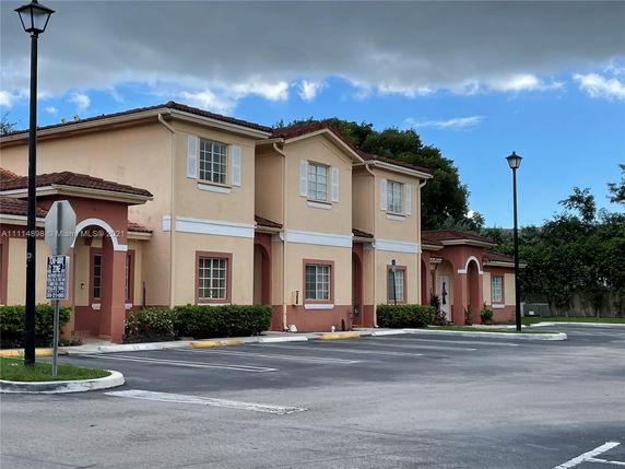 Front view of a two-story residential building with a parking area in front.