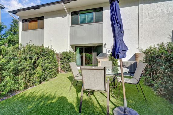 Rear view of a two-story house with a small patio area and outdoor furniture.