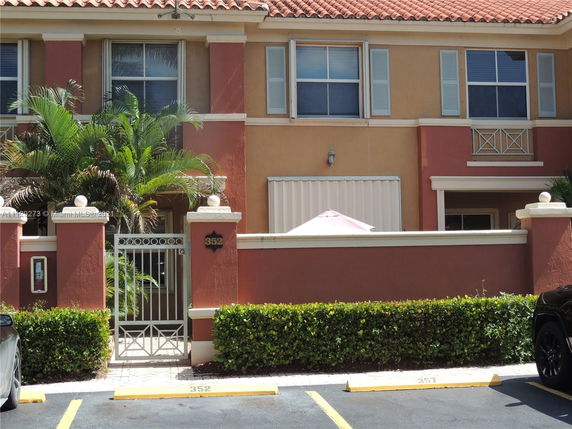 Front view of a townhouse with a gate and plants at the entrance.