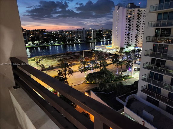 View from a balcony overlooking a river and cityscape at dusk.