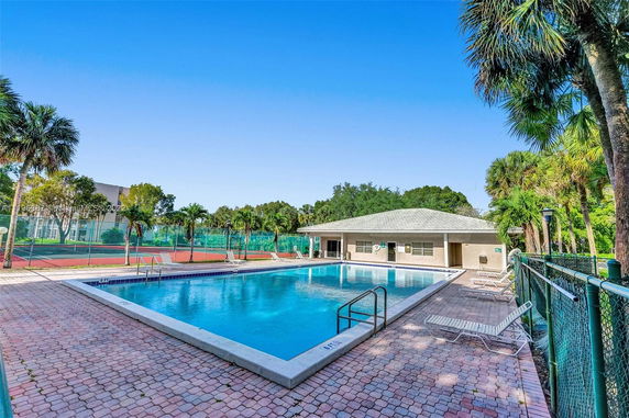 Outdoor swimming pool with a nearby building and surrounding trees.