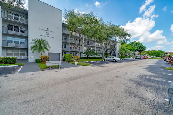 Front view of a multi-story residential building with balconies and trees.