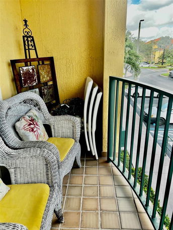 Balcony view with wicker chairs and a railing overlooking parking lot.