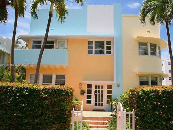 Front view of a two-story building with tropical design elements, featuring pastel blue and yellow hues.