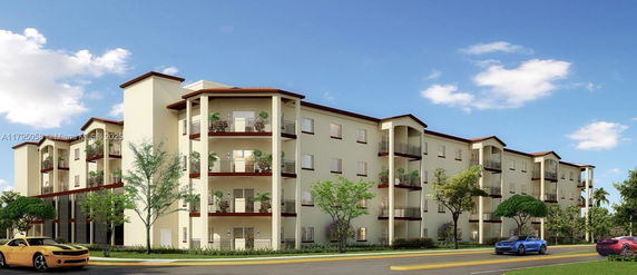 Front view of a multi-story apartment building with balconies and decorative greenery.