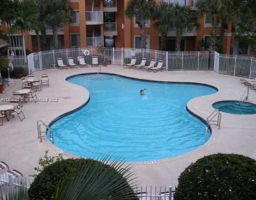 Outdoor swimming pool area with surrounding lounge chairs and a small jacuzzi.