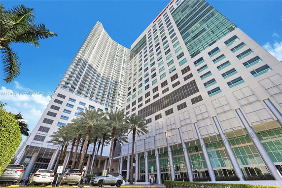Front view of a modern multi-story high-rise building with large glass windows and multiple balconies.