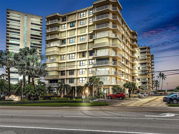 Front view of a multi-story residential building with balconies and a parking area.