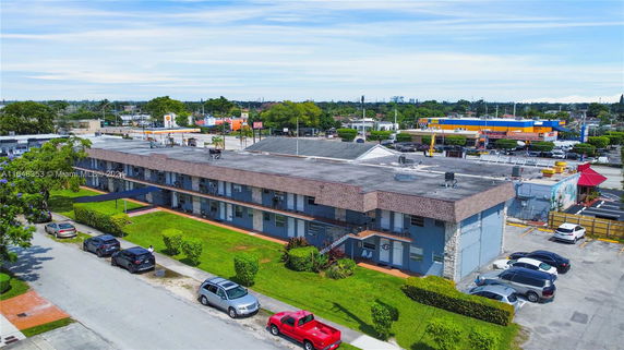 Side view of a two-story commercial building with multiple entrances, surrounded by parked cars.