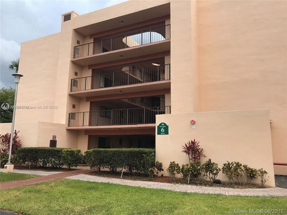 Front view of a multi-story building with balconies and beige exterior.