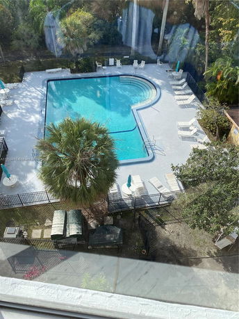 Aerial view of an outdoor swimming pool with surrounding lounge chairs and greenery.