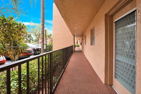 View of a corridor with railing and parked cars visible outside.