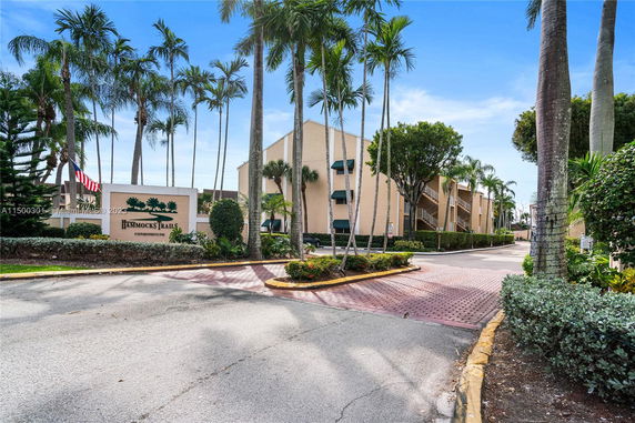 Front view of a multi-story condominium building with palm trees.